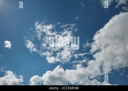 Azure sky with clouds lit by bright sun. The sun`s rays lit up a blue heaven covered with clouds. Background for forecast and meteorology illustration Stock Photo